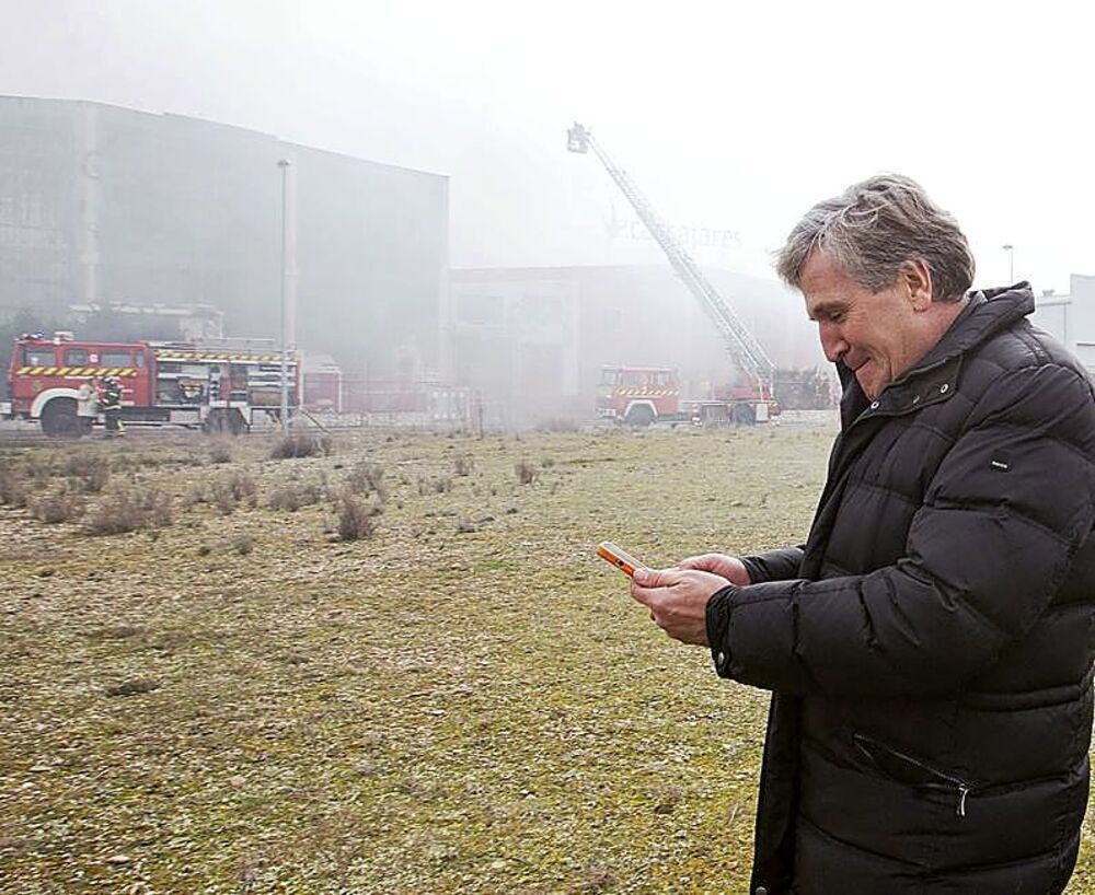 Alfonso Jiménez mira el teléfono frente a las instalaciones devoradas por las llamas.